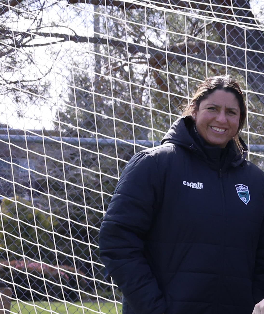 Coach Savanna Dickson in a black Capelli WPFC jacket standing in front of a soccer goal
