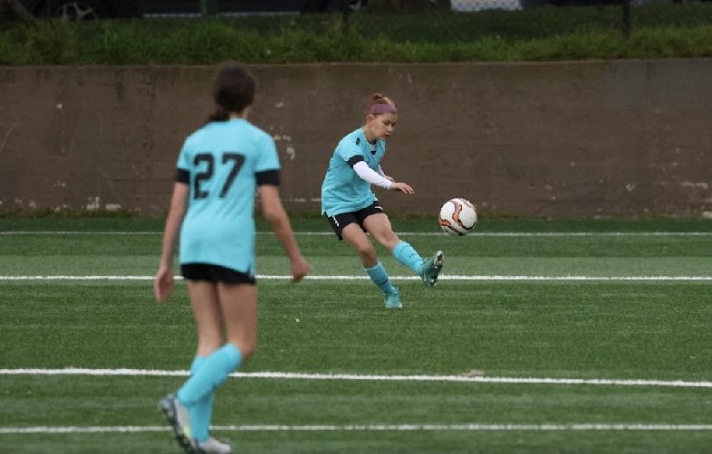 Youth player in mint kit striking a ball during a pod session